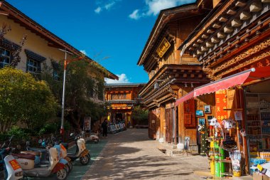Shangri-La, Çin - 20 Ekim 2024 Dukezong Antik Kasabası 'nda canlı bir cadde geleneksel ahşap binalar ve parlak bir gökyüzünün altındaki dükkanlarla dolu..