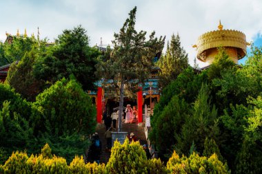 Shangri-La, Çin - 20 Ekim 2024: Geleneksel tapınaklar ve devasa altın dua çarkları Guishan Park, Shangri-La 'da yemyeşil bir yamaç..