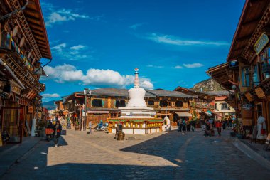 Shangri-La, Çin - 20 Ekim 2024 Dukezong Antik Kenti 'nin hareketli meydanında altın dua tekerleriyle önde gelen beyaz bir stupa duruyor..