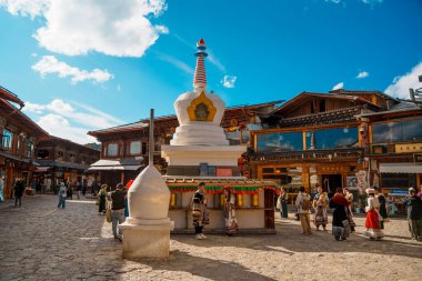 Shangri-La, Çin - 20 Ekim 2024 Dukezong Antik Kenti 'nin hareketli meydanında altın dua tekerleriyle önde gelen beyaz bir stupa duruyor..
