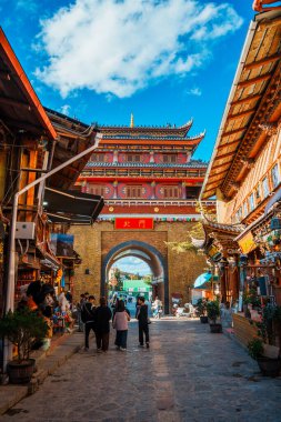 Shangri-La, Çin - 20 Ekim 2024: Turistler, açık mavi bir gökyüzü altında Dukezong Antik Kenti 'nin geleneksel kemerinde yürüyorlar.