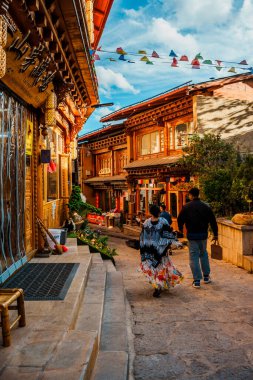 Shangri-La, Çin - 20 Ekim 2024 Dukezong Antik Kasabası 'nda canlı bir cadde geleneksel ahşap binalar ve parlak bir gökyüzünün altındaki dükkanlarla dolu..