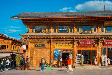Shangri-La, Çin - 20 Ekim 2024 Dukezong Antik Kasabası 'nda canlı bir cadde geleneksel ahşap binalar ve parlak bir gökyüzünün altındaki dükkanlarla dolu..