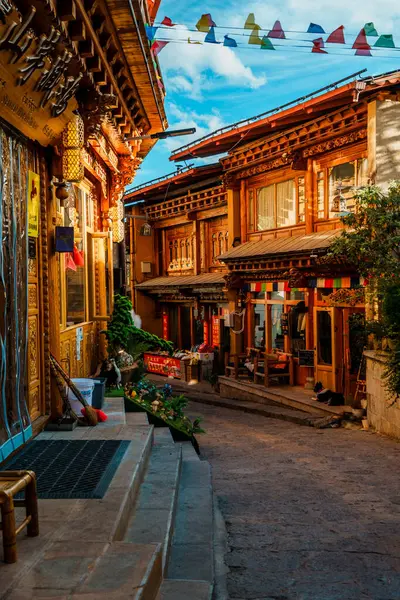 Shangri-La, Çin - 20 Ekim 2024 Dukezong Antik Kasabası 'nda canlı bir cadde geleneksel ahşap binalar ve parlak bir gökyüzünün altındaki dükkanlarla dolu..