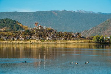 Şangri La 'nın tarihi şehrinin çarpıcı güneşli bir manzarası. Geleneksel mimarisi derin mavi bir göle yansıyor..