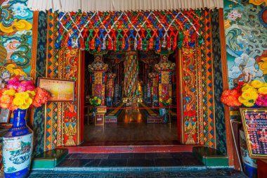 Songzanlin Manastırı 'ndaki dinsel sanat ve sütunlarla süslenmiş canlı bir dua salonunun simetrik görüntüsü..