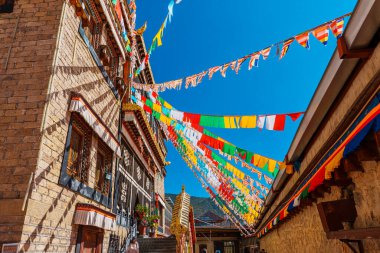 Songzanlin Manastırı 'nın mimarisi açık mavi gökyüzüne karşı dalgalanan renkli dua bayraklarıyla.