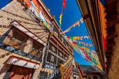 Songzanlin Manastırı 'nın mimarisi açık mavi gökyüzüne karşı dalgalanan renkli dua bayraklarıyla.