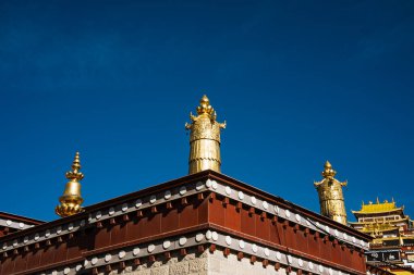 Çin 'in Yunnan kentindeki Songzanlin Manastırı' nda mavi gökyüzüne karşı yaldızlı çatı süsleri. Budist mimarisinin bir sembolü..