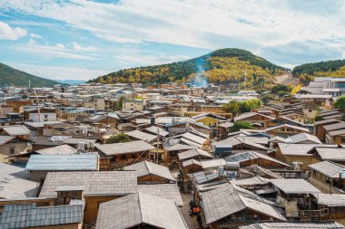 Shangri-La 'nın eski kasabasının geleneksel kiremitli çatılarının geniş açılı manzarası ve arkasında dağlar var..