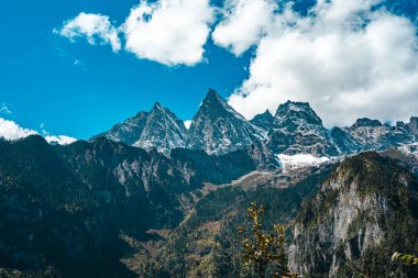Balagezong Büyük Kanyonu 'nda, Şangri-La' da, Yunnan 'da, Çin' de bulutlu mavi gökyüzünün altında seyrek kar yağan pürüzlü ve dramatik bir dağ sırası..