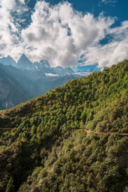Kıvrımlı yürüyüş yolları ve kablo hatları Balagezong Sahne Bölgesi, Şangri-la, Çin 'deki ormanlık tepeler boyunca uzanıyor.