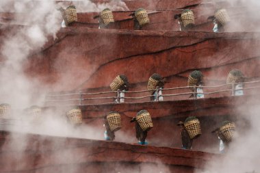Lijiang, Çin - 24 Ekim 2024: Etnik kostümlü düzinelerce sanatçı, Lijiang Esintisi sırasında yükselen sis ortamında kırmızı teraslı dramatik bir sahne boyunca poz verdiler.