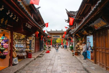 Lijiang, Çin - 25 Ekim 2024: Çin bayrakları ve Çin 'in Yunnan kentindeki geleneksel ahşap binalarla süslenmiş dar kaldırım taşı caddesi.
