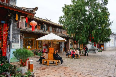 Lijiang, Çin - 25 Ekim 2024: Lijiang Eski Kasabası, Yunnan 'ın canlı pazarında asılı tabelaları, çiçekleri ve açık hava oturma yerleri olan geleneksel Çin dükkanları.