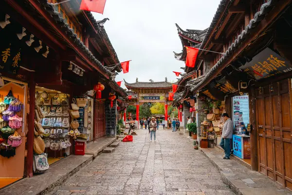 Lijiang, Çin - 25 Ekim 2024: Çin bayrakları ve Çin 'in Yunnan kentindeki geleneksel ahşap binalarla süslenmiş dar kaldırım taşı caddesi.