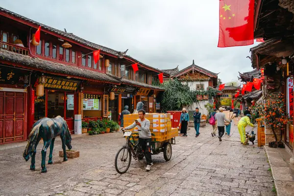 Lijiang, Çin - 25 Ekim 2024: Lijiang Eski Kasabası 'nda el arabaları, satıcılar ve tarihi Çin mimarisi ile dolu bir meydan, Yunnan' daki UNESCO Dünya Mirası Bölgesi.