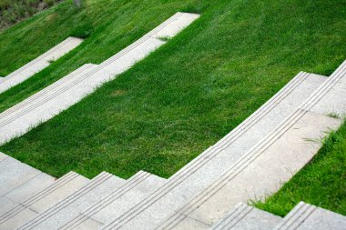 Yaz parkında tepedeki çimlerin yakınına granit basamaklı merdivenler..