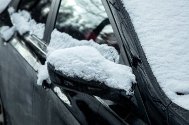 Siyah araba kar tabakasıyla kaplı, dikiz aynası kışın erken saatlerinde atmosferik yağış var, kimse yok..