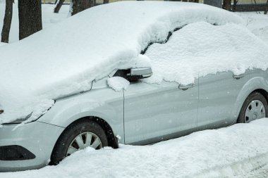 Otoparkta kar yığınıyla kaplı gri araba, karlı bahar sabahı faciası..
