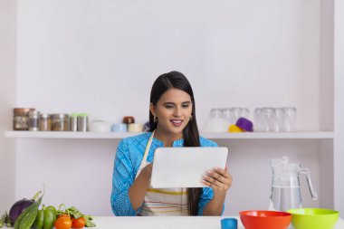 Hintli kadın yemek tarifini mutfakta tabletten öğreniyor.