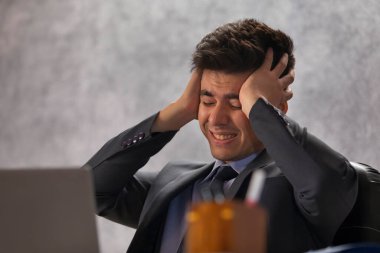 Ofisinde elleri başında oturan stresli genç bir iş adamının portresi.