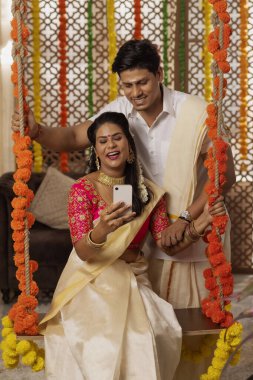 Güney Hintli çift evde Onam kutlarken cep telefonu kullanıyor.