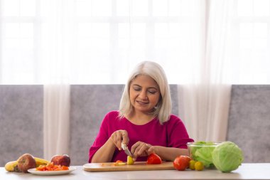 Mutfakta sebze doğrayan yaşlı kadın.