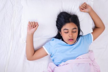 Evdeki yatakta uyuyan bir kızın portresi.