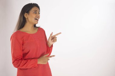 Beyaz arka planda ayakta duran neşeli genç bir kadının portresi.