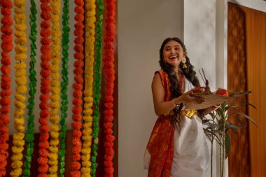 Durga Puja vesilesiyle Puja Thali 'nin yanında duran beyaz elbiseli Bengalli kadın.