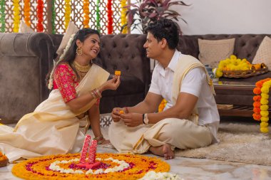 Güney Hintli çift Onam 'ı kutlamak için çiçek çelengi ile evi dekore ediyorlar.