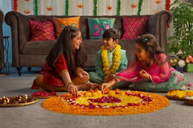 Çocuklar Diwali 'de yerleri çiçeklerle süslerken (Rangoli) eğleniyorlar.