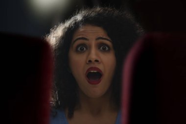 Sinema salonunda korku filmi izlerken şok olmuş ve şaşırmış bir kadının portresi.