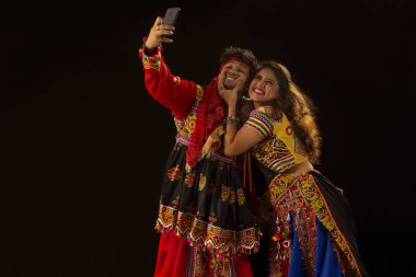 A  happy young couple taking.a selfie, during Navratri celebrations clipart