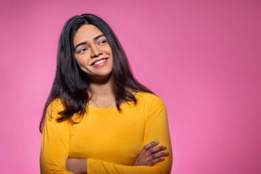 Portrait of a happy young woman looking elsewhere with hands crossed clipart