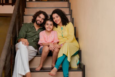 Aile üyeleri merdivenlerde oturuyor ve kameraların önünde birlikte poz veriyorlar.