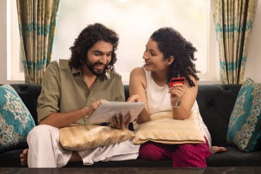 Genç çift kredi kartıyla tablet üzerinden alışveriş yapıyor.