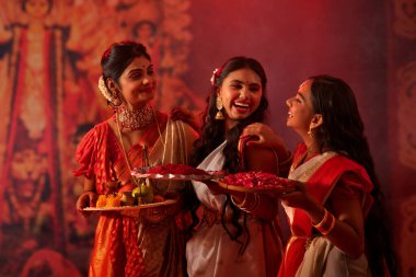 Durga Puja kutlamaları sırasında anneleri ve kızları puja thali ile birlikte duruyorlar.