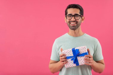 Elinde hediyeyle kameraya bakan mutlu genç adamın portresi.