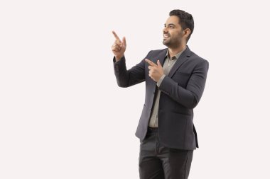 Neşeli genç işadamı beyaz arka plana işaret ediyor