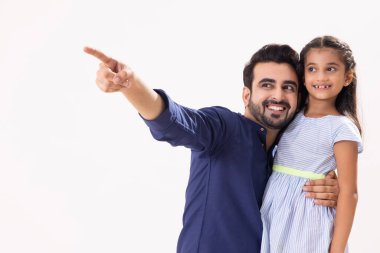 Bir baba, kızını kucağında tutarken başka bir yeri işaret ederek mutlu olur.