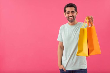 Alışveriş torbaları ve el ele duran mutlu genç adam.