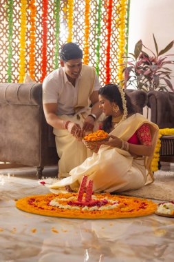 Güney Hintli çift Onam 'ı kutlamak için çiçek çelengi ile evi dekore ediyorlar.