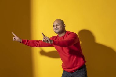 Düz arkaplanda dans eden kel bir adamın portresi.