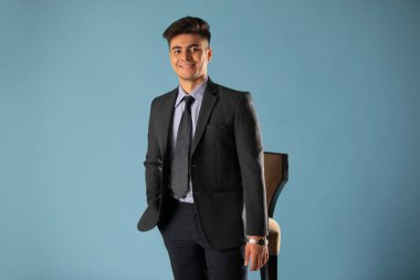 Mavi arka planda kameraya bakan genç bir iş adamının portresi.