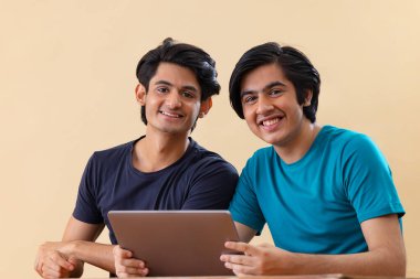 Arka planda dijital tablet kullanan iki gencin portresi