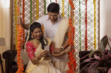 Güney Hintli çift evde Onam kutlarken cep telefonu kullanıyor.