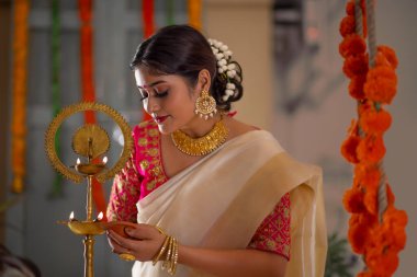 Onam vesilesiyle beyaz sari giymiş bir kadın parlıyor.