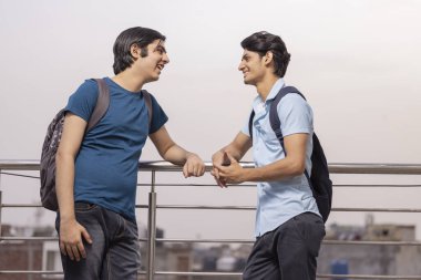 İki genç arkadaş korkulukların yanında konuşurken